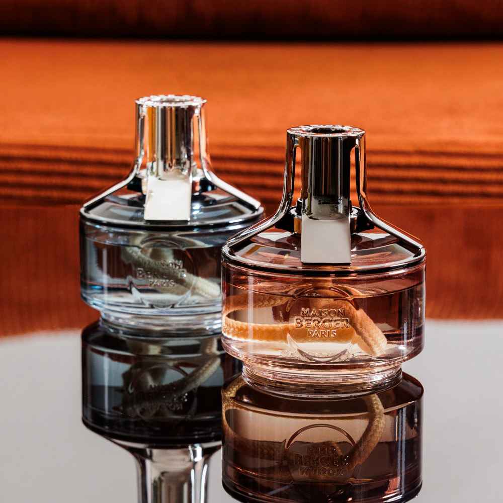 Pareja de lámparas catalíticas Identity Maison Berger en cristal gris y ámbar con cordón trenzado y reflejo sobre superficie espejada – D'Arome