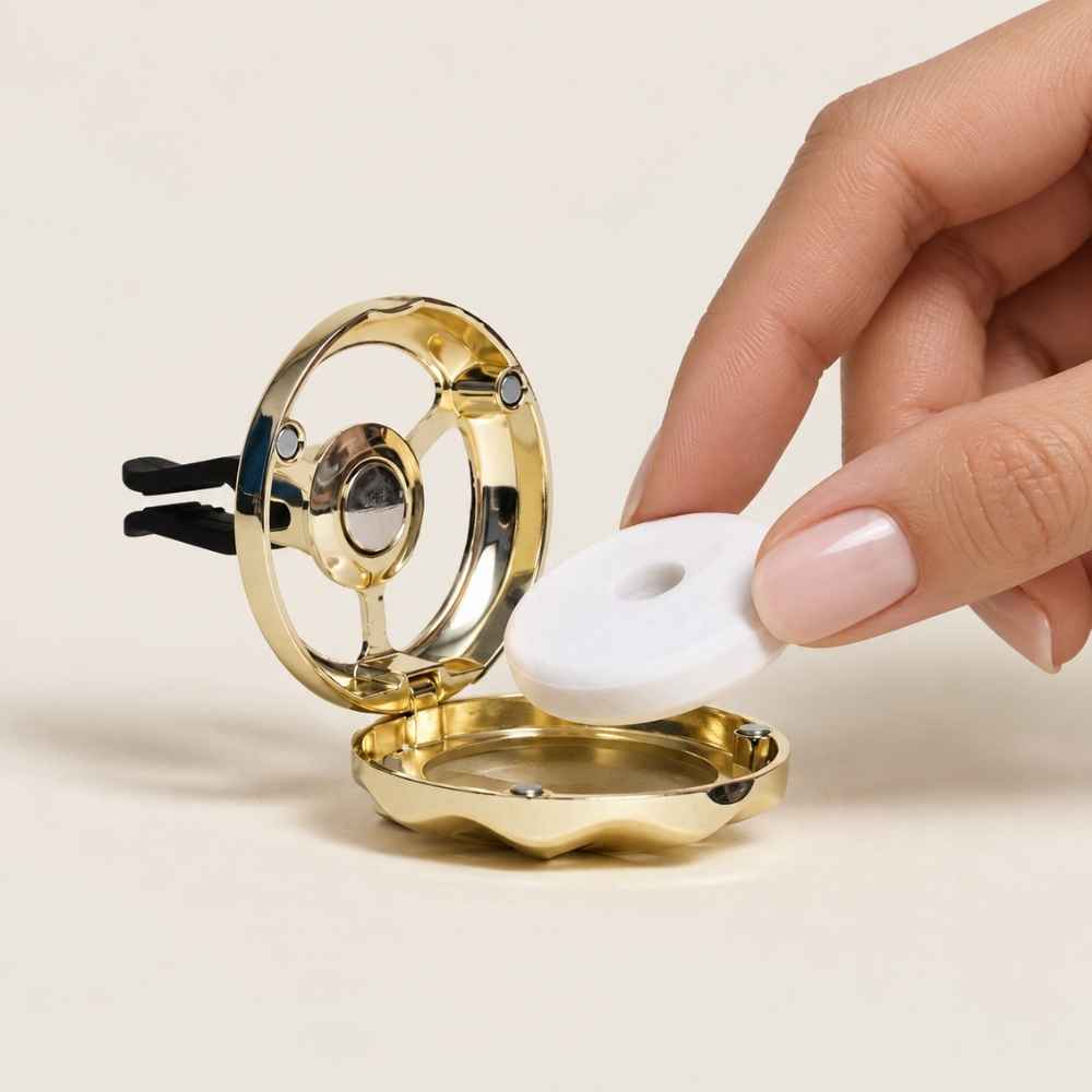 Detalle de mano insertando el recambio perfumado en el difusor de coche dorado Maison Berger – D'Arome