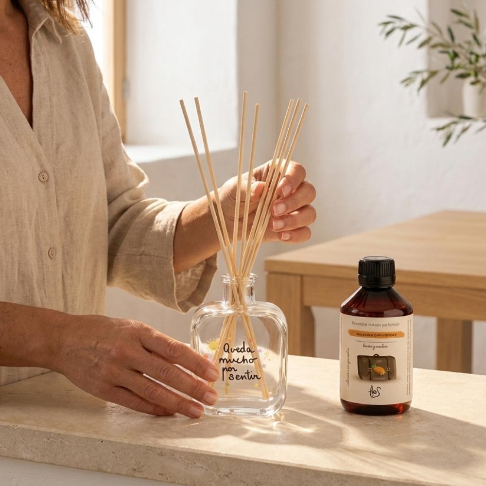 Manos colocando los palos en el mikado Nuevos Comienzos LoeS limón y azahar con recambio 250ml al lado, cómo rellenar un mikado perfumado – D'Arome