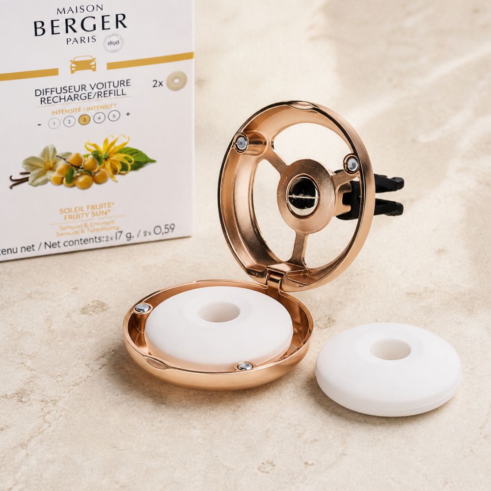 Primer plano del difusor Maison Berger de oro rosa abierto con una pastilla de cerámica blanca dentro y otra fuera, junto a la caja de recargas Soleil Fruité.