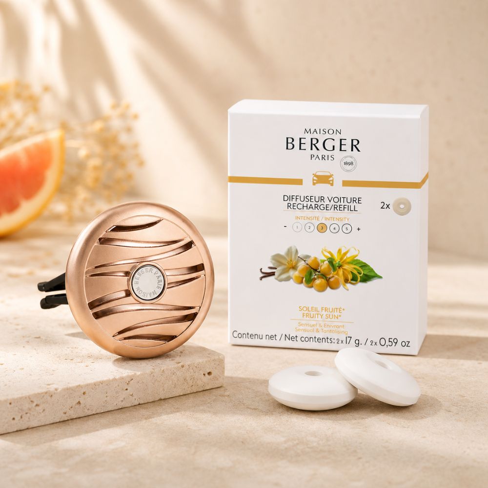 Bodegón de producto con la caja de recargas Maison Berger Soleil Fruité, el difusor de oro rosa, dos pastillas de cerámica y media toronja sobre una base de piedra.