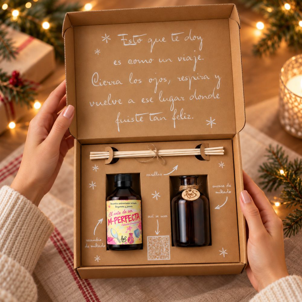 Manos abriendo el cofre regalo de Navidad 'Una Navidad im-perfecta' con mikado LoeS sobre una mesa con luces navideñas – D'Arome