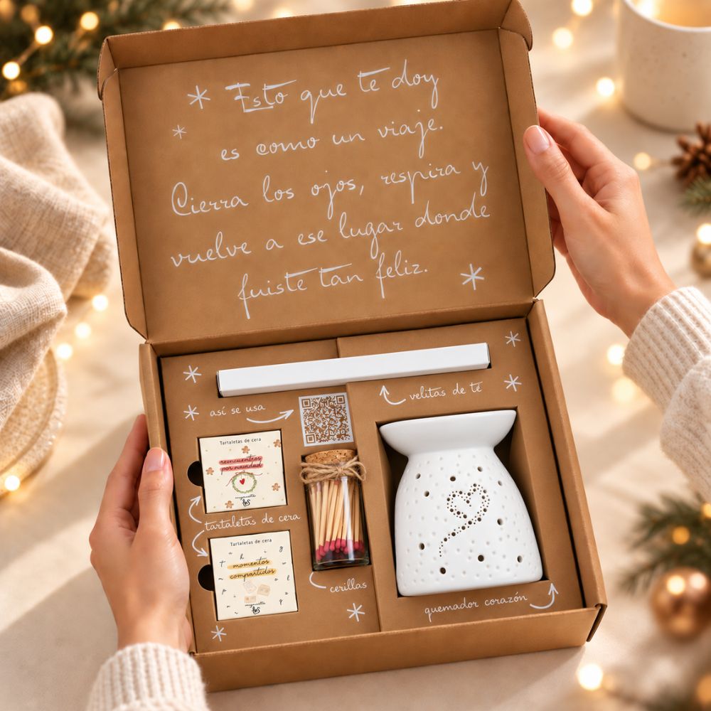 Manos abriendo el cofre regalo 'Enciende la Navidad' con quemador de cera de cerámica blanca y tartaletas perfumadas LoeS – D'Arome