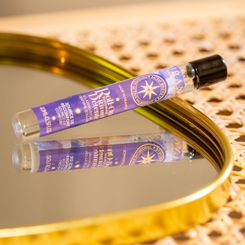 Roll-on perfumado Rituel Détente Durance tumbado sobre bandeja espejada con reflejo del envase – D'Arome