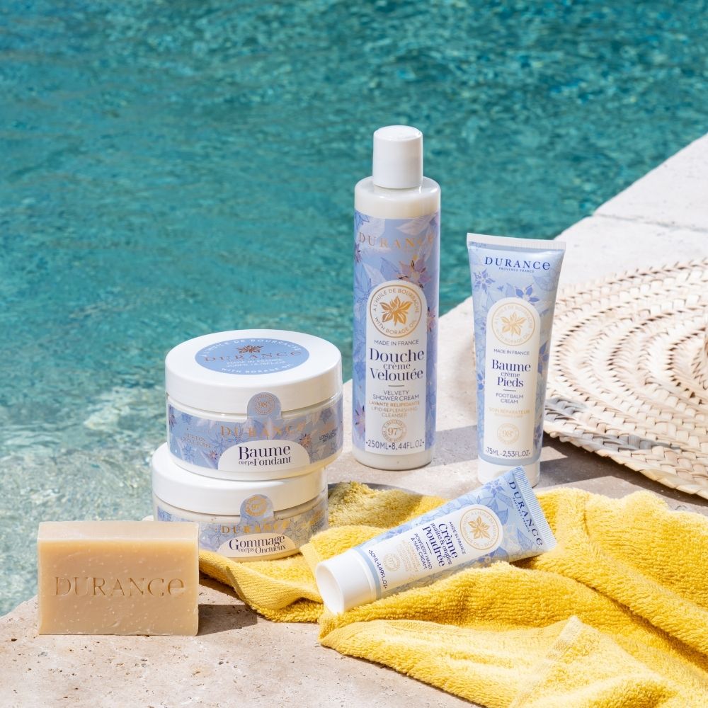 Set corporal con aceite de borraja Durance: bálsamo, exfoliante, crema de ducha, crema del cuerpo y bálsamo de pies junto a piscina en un ambiente de verano – D'Arome