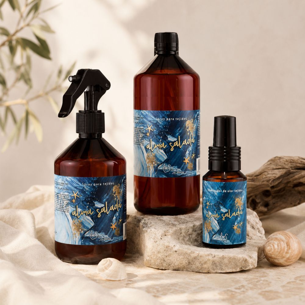 Comparativa de los tres formatos del spray textil Alma Salada de LoeS: 500 ml pulverizador, recambio de 1 litro y mini de 50 ml sobre piedra natural con conchas – D'Arome