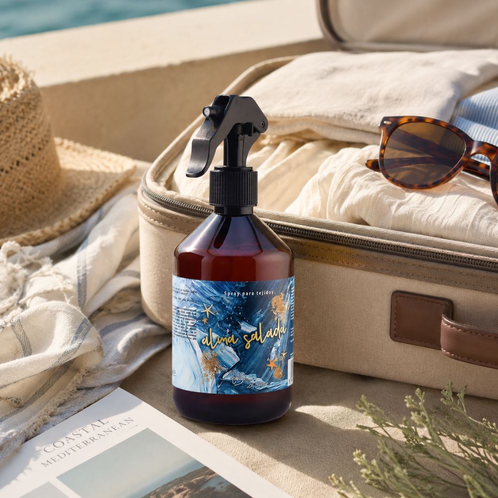 Spray para tejidos Alma Salada de LoeS junto a una maleta de viaje con pareo, gafas de sol y revista de inspiración mediterránea – D'Arome