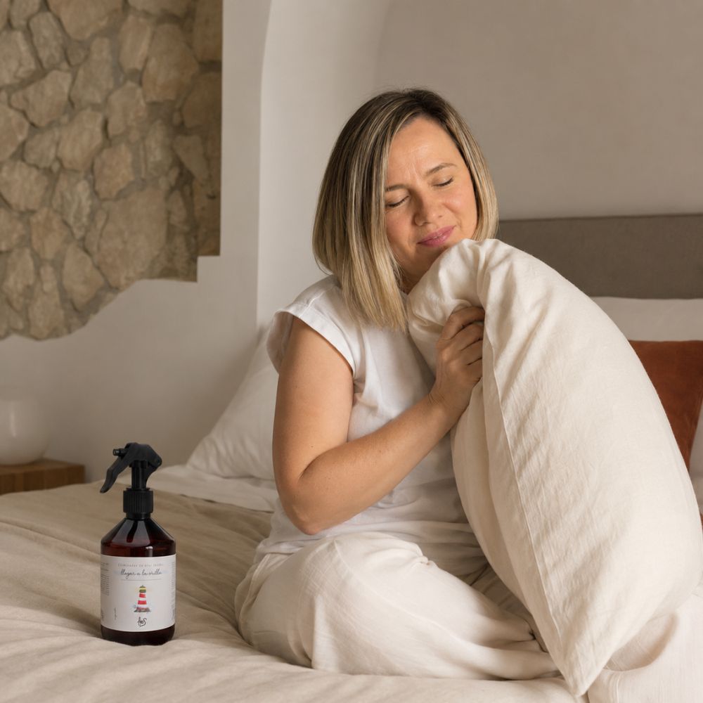Ana Belén, embajadora de D'Arome, disfrutando el aroma del spray textil eliminador de olor para tejidos Llegar a la Orilla de LoeS en la almohada del dormitorio – D'Arome