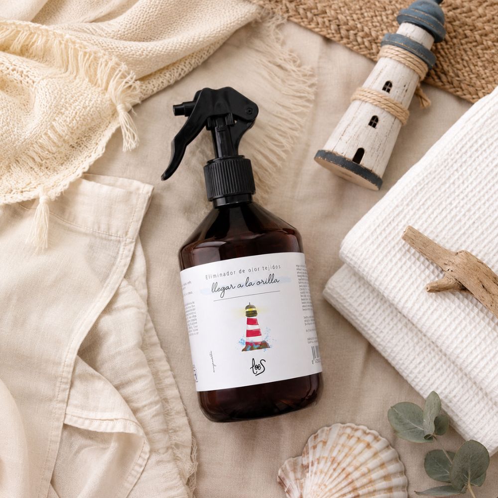 Spray textil eliminador de olor para tejidos Llegar a la Orilla de LoeS en bodegón marino con faro de madera, conchas y eucalipto sobre lino – D'Arome
