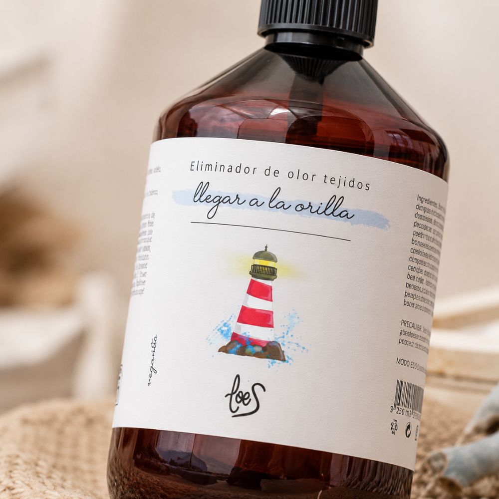 Detalle de la etiqueta del spray textil eliminador de olor para tejidos Llegar a la Orilla de LoeS con la ilustración del faro marino, marca propia D'Arome