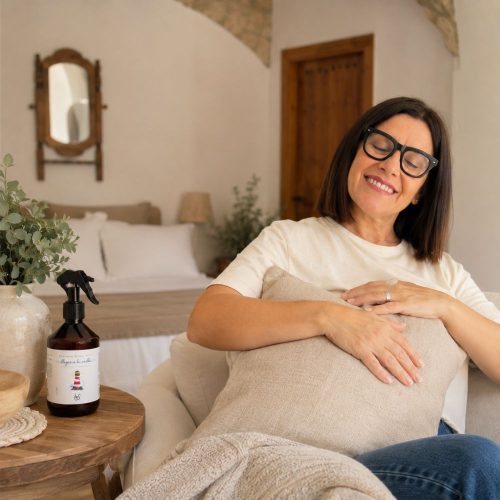 Mari Carmen, CEO y experta en aromas de D'Arome, disfrutando el aroma del spray textil eliminador de olor para tejidos Llegar a la Orilla de LoeS abrazando un cojín – D'Arome
