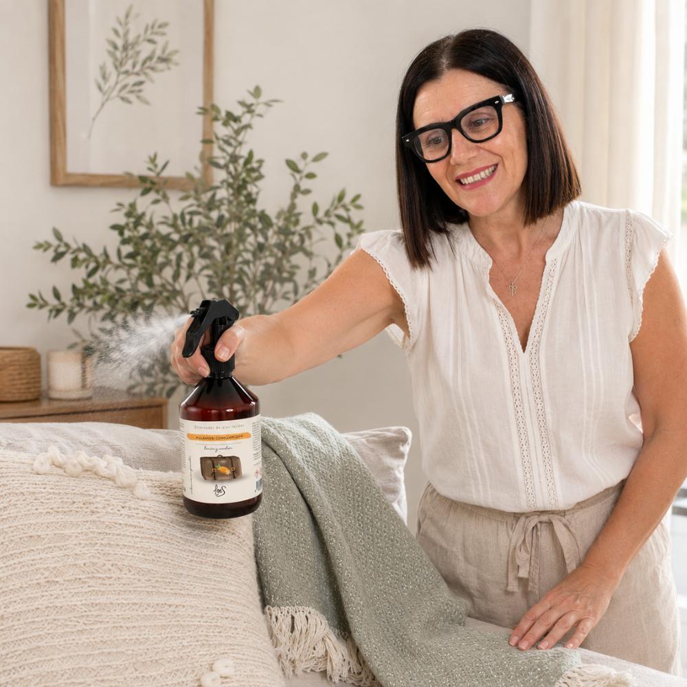 Mari Carmen, CEO y experta en aromas de D'Arome, pulveriza el spray textil Nuevos Comienzos de LoeS sobre cojines y manta del sofá para eliminar olores – D'Arome