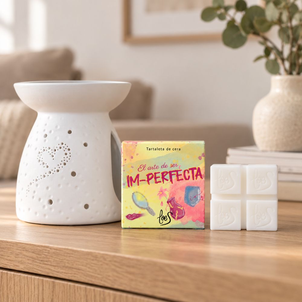 Tartaleta de cera perfumada Im-Perfecta de LoeS junto a un quemador de cerámica calado con forma de corazón, sobre una mesa de madera – D'Arome