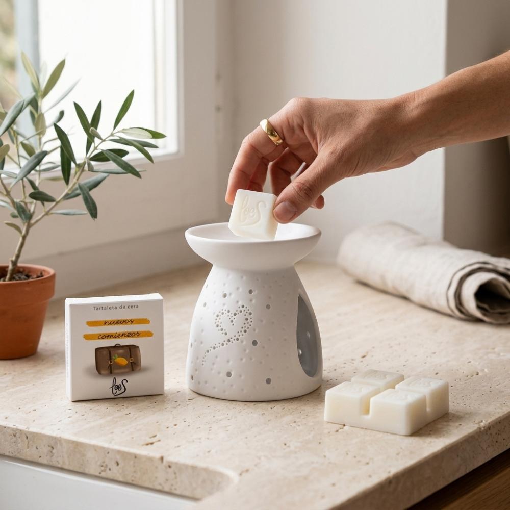 Mano colocando una pieza de tartaleta de cera Nuevos Comienzos LoeS limón y azahar en quemador cerámico blanco, cómo usar wax melt – D'Arome