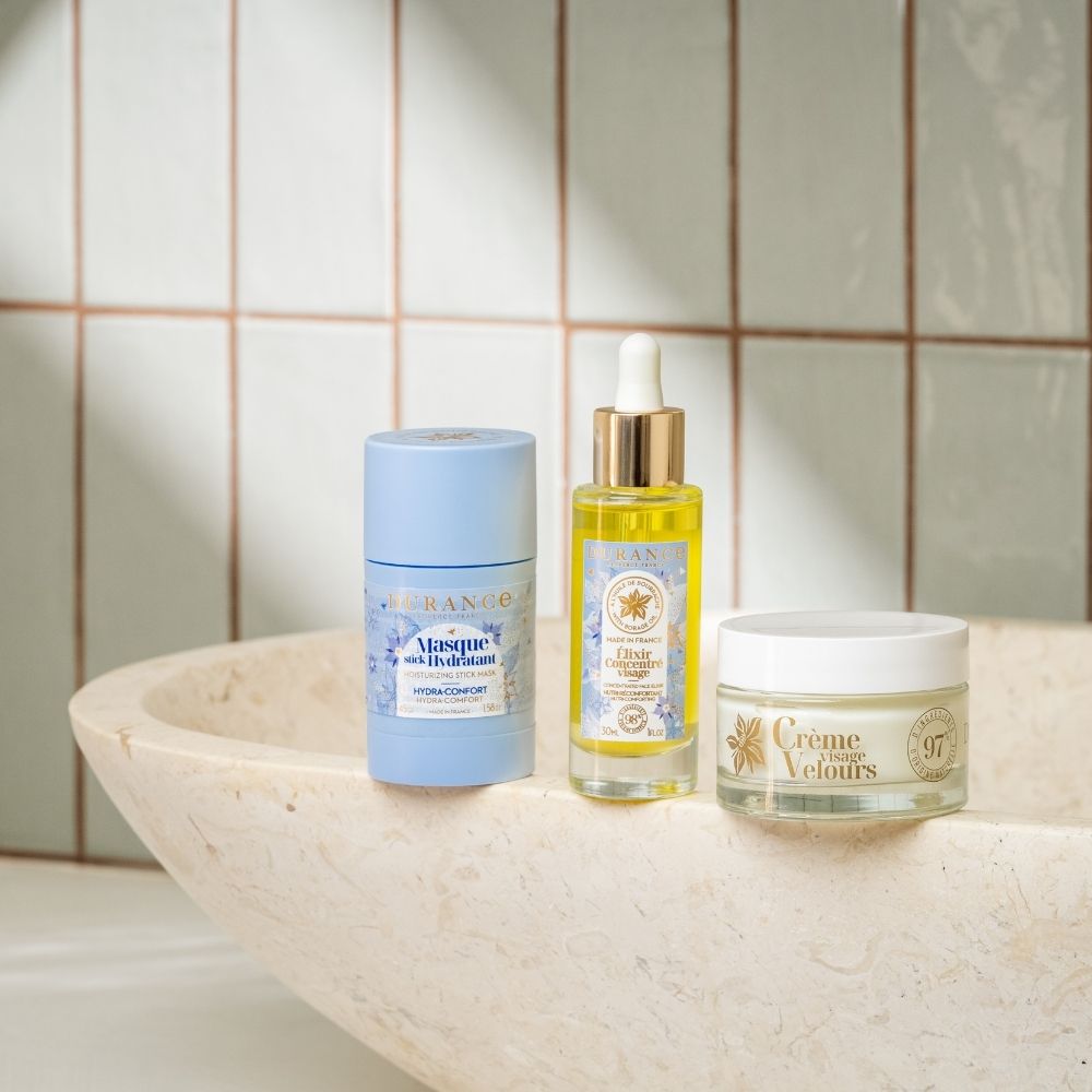 Trío de cuidado facial Durance con mascarilla stick hidratante, elixir concentrado y crema visage velours sobre lavabo de piedra – D'Arome