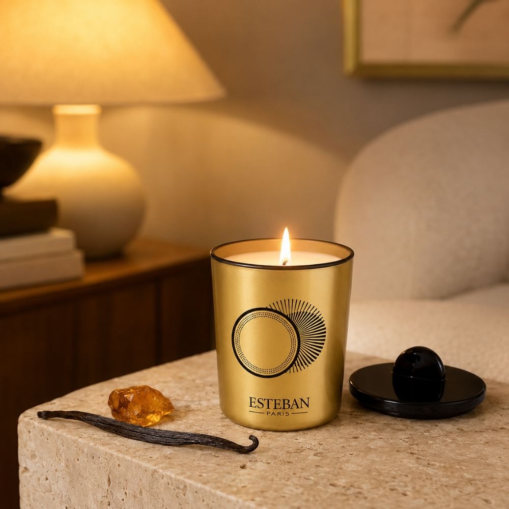 Vela decorativa perfumada recargable Ambre et Vanille Étoilée Esteban París encendida junto a vaina de vainilla y resina de ámbar en salon cálido – D'Arome