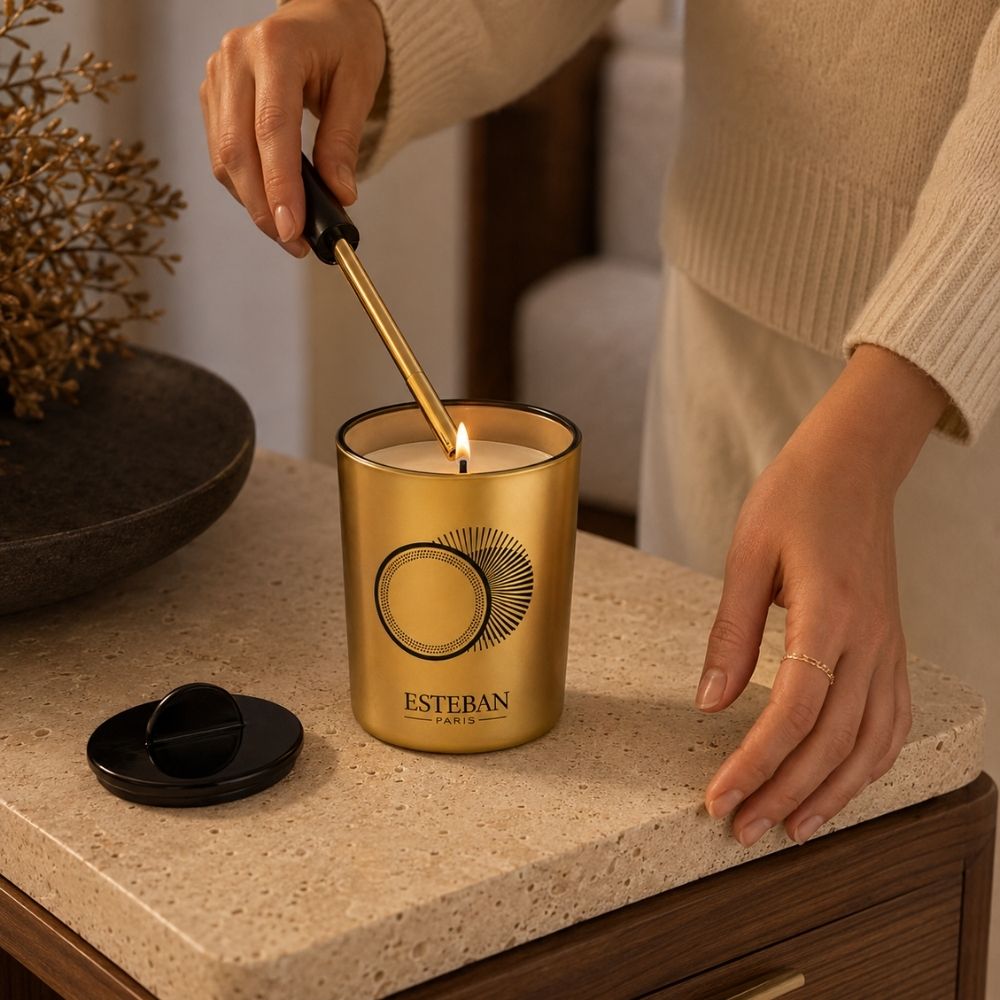 Detalle de manos encendiendo con un mechero la vela decorativa perfumada recargable Ambre et Vanille Étoilée Esteban París – D'Arome