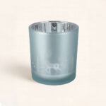 Portavelas Blanca Navidad Azul con diseño de renos y abetos. Luz suave y reflejos plateados para una decoración navideña elegante y acogedora.